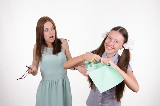 Schoolgirl having fun tearing the notebook in front of an angry teacher