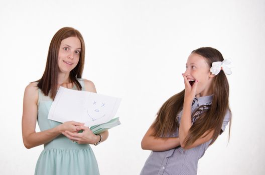 Teacher checking notebooks students saw one of them funny painted a face