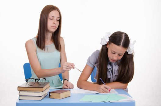 Teacher teaches the student sitting with him at the table