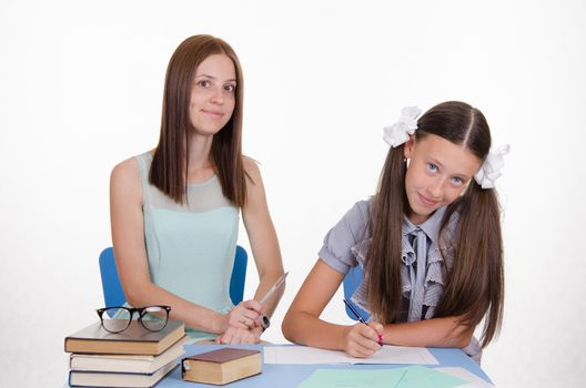 Teacher teaches the student sitting with him at the table