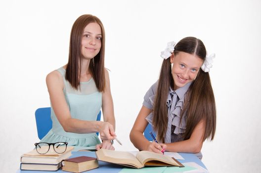 Teacher teaches the student sitting with him at the table