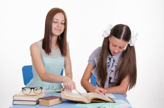 Teacher teaches the student sitting with him at the table