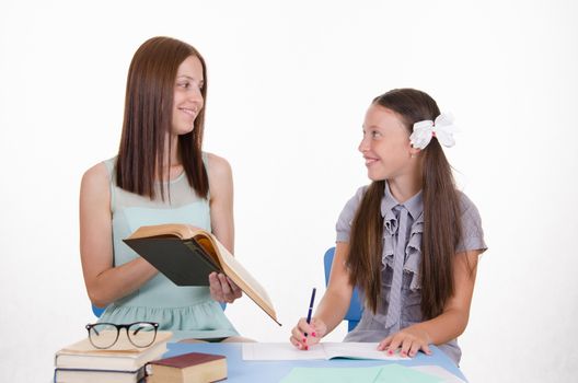 Teacher teaches the student sitting with him at the table