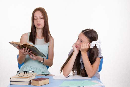 Teacher teaches the student sitting with him at the table