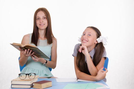 Teacher teaches the student sitting with him at the table