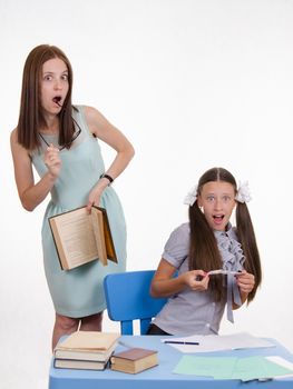 Teacher standing at desk behind which sits a pupil is deducted from the Crib