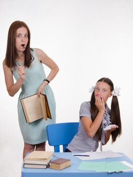 Teacher standing at desk behind which sits a pupil is deducted from the Crib