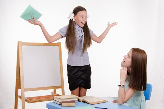 Pupil stands at the blackboard, the teacher sits at his desk and listens to the student