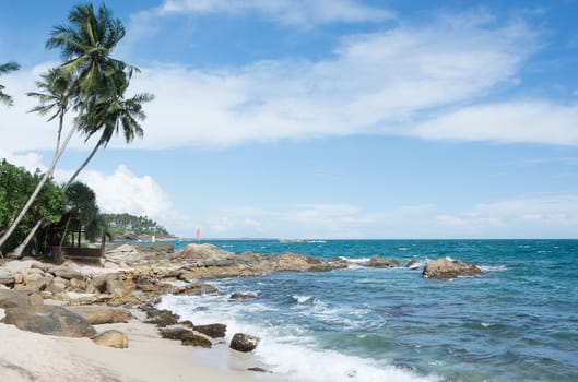 Tropical rocky beach with coconut palm trees, sandy beach and ocean. Tangalle, Southern Province, Sri Lanka, Asia.