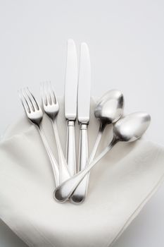 elegant silverware on a pile of plates with white cloth