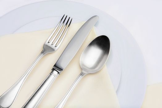 closeup of silverware on plates with yellow cloth