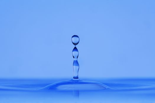blue droplet hitting the water surface splashing it up