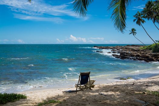 Tropical rocky beach with coconut palm trees, sandy beach and ocean. Tangalle, Southern Province, Sri Lanka, Asia.