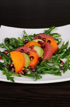 Salad with avocado, grapefruit, persimmon, pomegranate and arugula