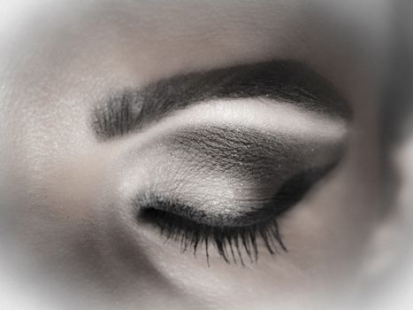 Closed eye makeup with shades of gray and black line.