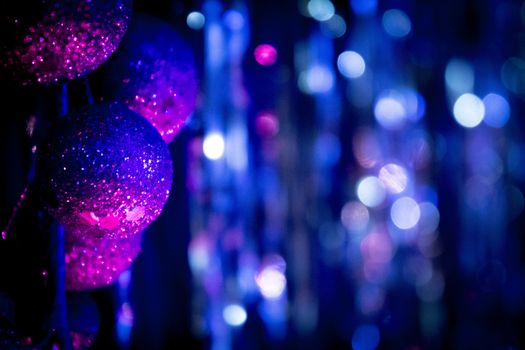 Christmas Xmas nativity decorative blue and pink balls against a blue and purple out of focus background of bokeh lights. 
Horizontal rectangular artistic digital color photo with shallow depth of focus.