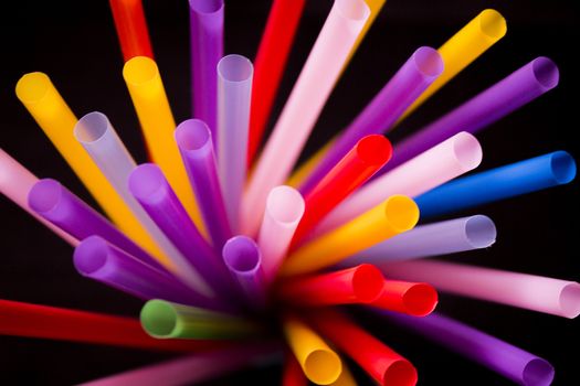 Drinking straws of all colors on black background.