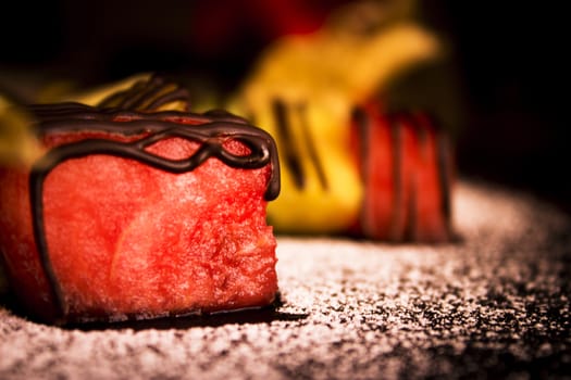 Set of fruits predominance of watermelon, on dark background, with watermelon and kiwi with defocused in the background, on icing sugar.