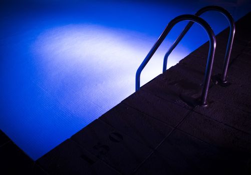 Part of a pool with stairs. Blue water.