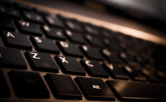 Part of computer keyboard in dark color. White letters.