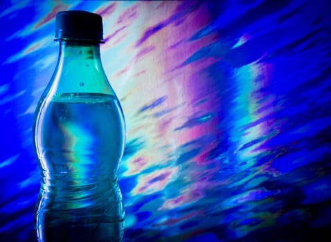 Bottle of water on abstract background in blue and purple tones.