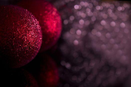 Red Christmas baubles on background of defocused purple lights.