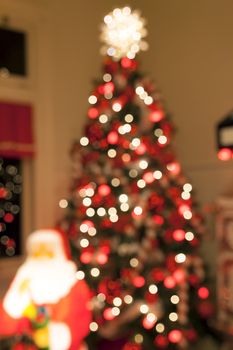 Christmas Tree Decorated with Lights Candy Cane Ornaments Tree Topper and Santa Claus Statue Blurred Defocused Bokeh Background