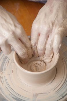 Hands of a potter, creating an earthen jar on the circle