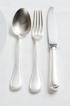 elegant silverware setting with plate and white cloth