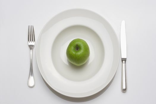 diet - green apple on a white plate with knife and fork