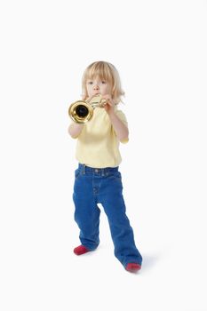 boy with long blond hair playing with toy trumpet