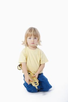 boy with long blond hair playing with toy trumpet