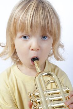 boy with long blond hair playing with toy trumpet