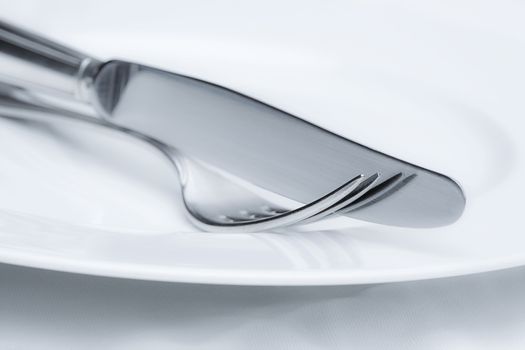 closeup of fork and knife silverware on white plate