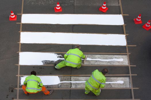 workers painting crosswalk with white colour - view from above