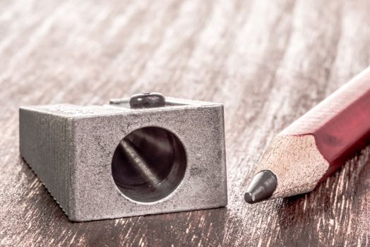 Close up view of a prism pensil sharpener and a pencil that needs some sharpening next to it.