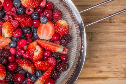 Mixed berries viewed from above as they lie spread out on a bamboo cutting board.