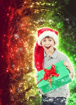 surprised boy in santa hat with christmas present on abstract christmas background