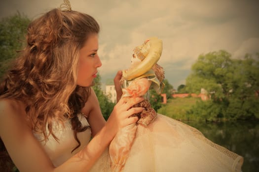 princess in white-golden gown plays with loved doll on background cloudy sky, instagram image style