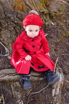Little girl wearing a red coat and hat in the forest