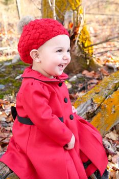 Little girl wearing a red coat and hat in the forest