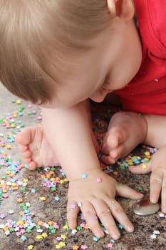 Baby boy playing with cake decorations on kitchen surface
