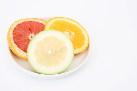 Sliced citrus fruits in a bowl on white background