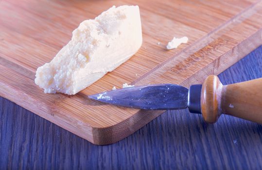 Grana Italian cheese over chopping board with blade