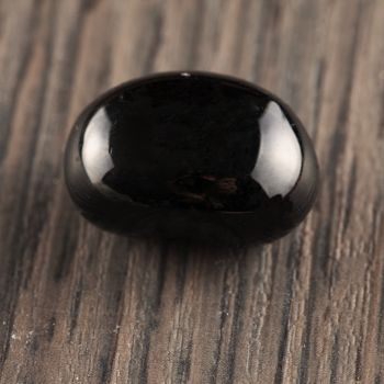Black stone over wooden background, square image
