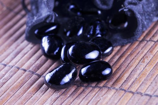 Black stones over wooden background, coming out of a bag