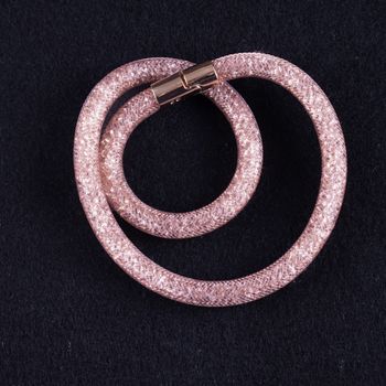 Shining pink bracelet over black tissue background