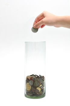 woman hand dropping coin into glass jar