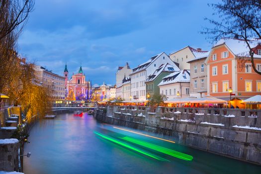 View of lively river Ljubljanica bank and Tromostovje in old city center decorated with Christmas lights at dusk. Ljubljana, Slovenia, Europe. 
