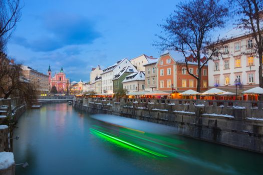 View of lively river Ljubljanica bank and Tromostovje in old city center decorated with Christmas lights at dusk. Ljubljana, Slovenia, Europe. 